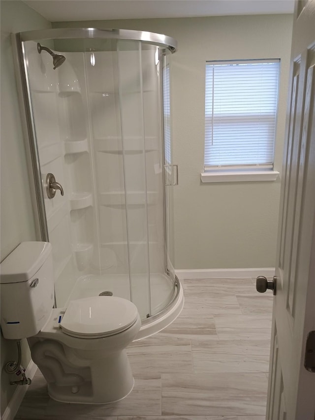 bathroom featuring toilet and a shower with shower door