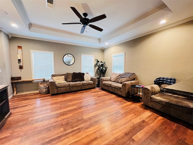 living area featuring light wood-style floors, a tray ceiling, and visible vents