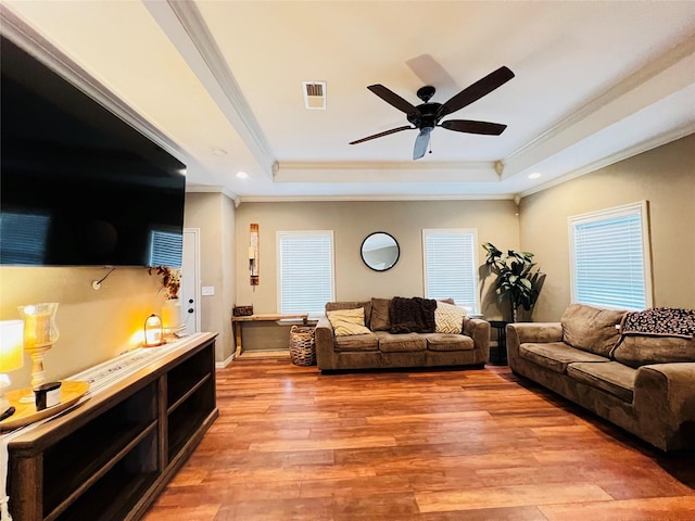 living room with ceiling fan, ornamental molding, a tray ceiling, and light hardwood / wood-style flooring