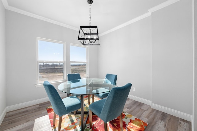 dining area featuring crown molding, an inviting chandelier, and light hardwood / wood-style flooring