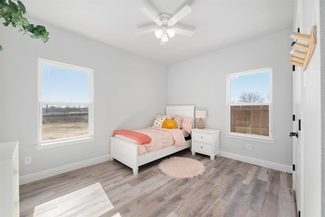 bedroom with ceiling fan, light hardwood / wood-style floors, and multiple windows