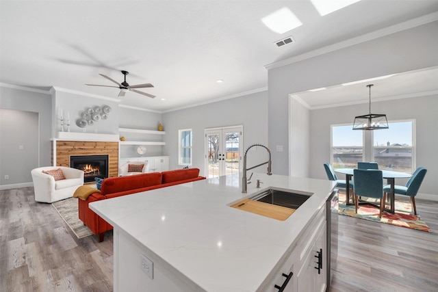 kitchen featuring white cabinetry, sink, a center island with sink, and decorative light fixtures