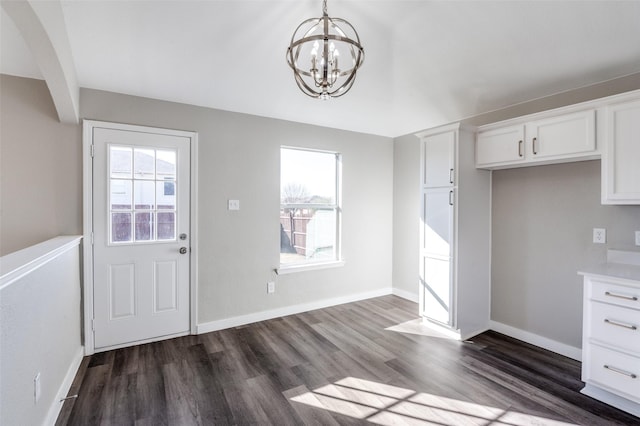 unfurnished dining area with a notable chandelier, dark hardwood / wood-style floors, and a wealth of natural light