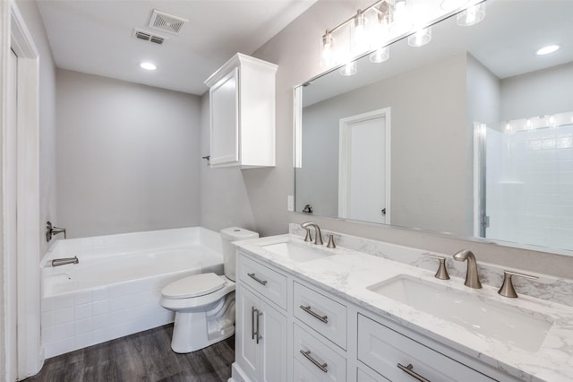 bathroom featuring vanity, toilet, hardwood / wood-style floors, and tiled tub