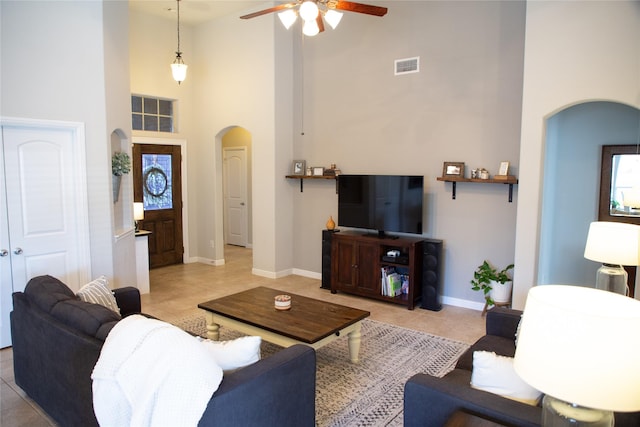 tiled living room featuring ceiling fan and a towering ceiling