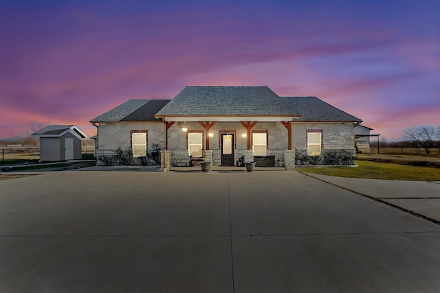 view of front of property featuring a porch and a storage shed