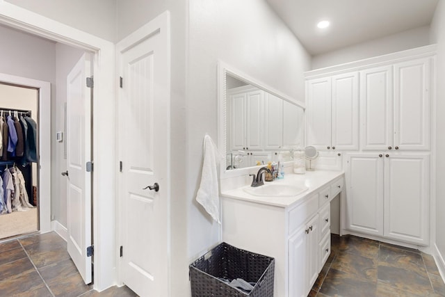 full bath featuring baseboards, stone finish flooring, a spacious closet, vanity, and recessed lighting