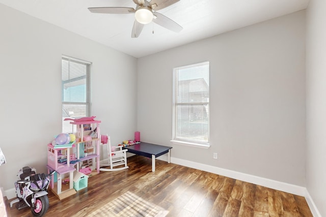 game room featuring a healthy amount of sunlight, ceiling fan, baseboards, and wood finished floors