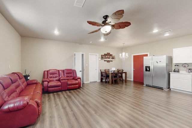 living room with light wood-style floors, visible vents, and ceiling fan with notable chandelier