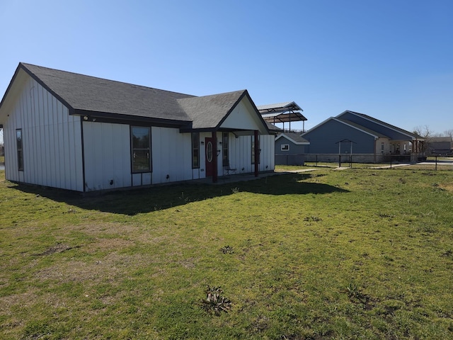 view of front of home with board and batten siding, fence, and a front lawn