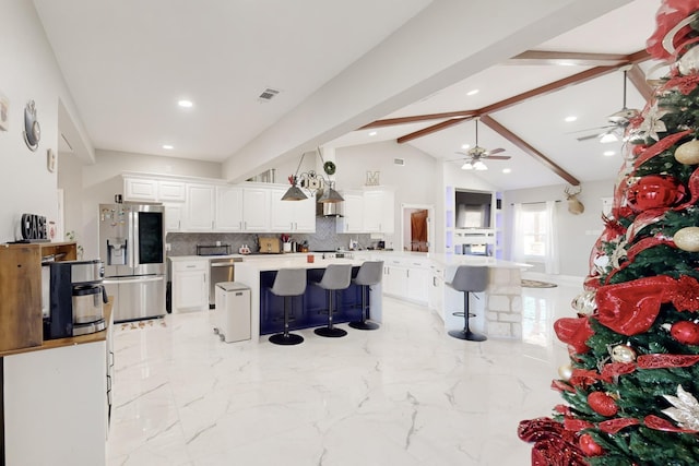 kitchen featuring visible vents, a kitchen bar, white cabinetry, stainless steel refrigerator with ice dispenser, and backsplash