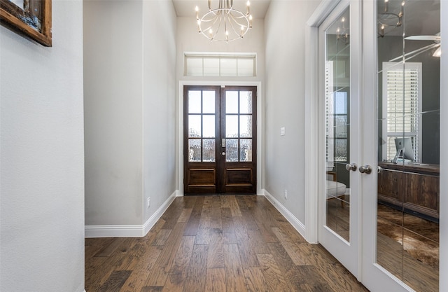 foyer entrance with french doors, dark hardwood / wood-style flooring, and a chandelier