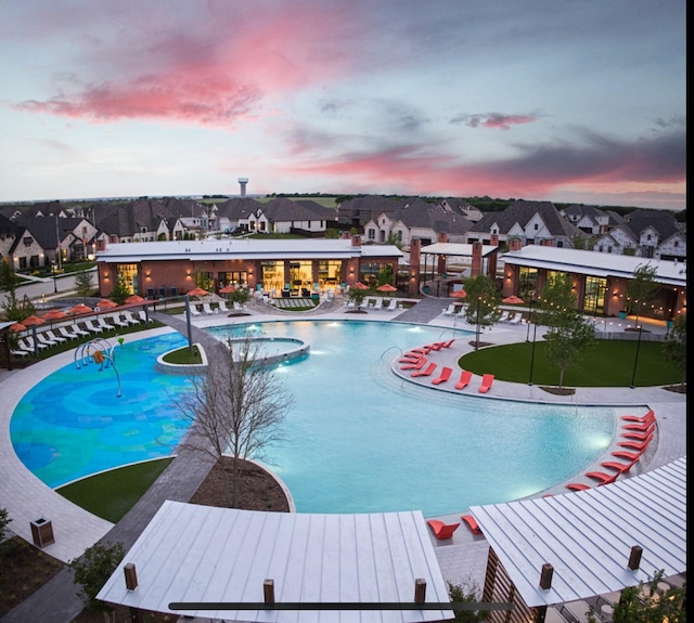 pool at dusk with a hot tub