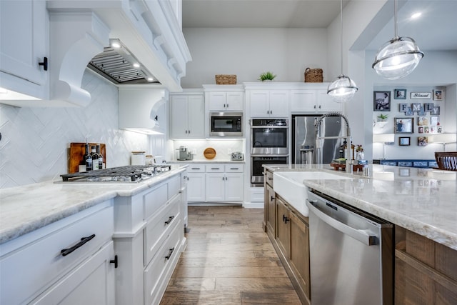 kitchen featuring decorative light fixtures, white cabinetry, decorative backsplash, light stone counters, and stainless steel appliances