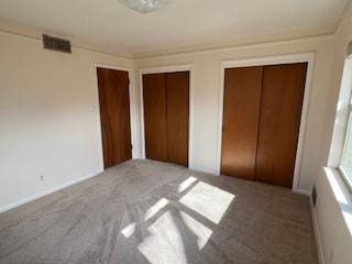 unfurnished bedroom featuring carpet flooring and two closets