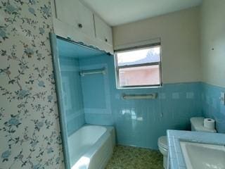 bathroom featuring vanity, toilet, tile walls, and a tub