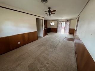 carpeted empty room featuring ceiling fan and wood walls