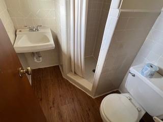 bathroom featuring wood-type flooring, toilet, and a shower