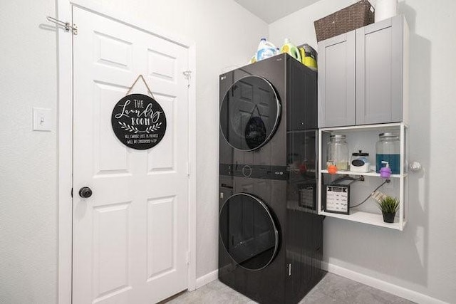 washroom featuring cabinets and stacked washer and clothes dryer