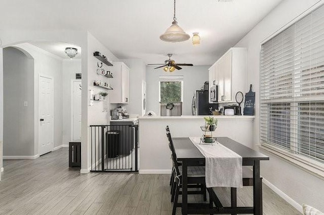 kitchen with stainless steel appliances, white cabinetry, hanging light fixtures, and kitchen peninsula