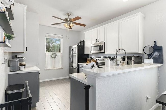 kitchen with white cabinetry, light hardwood / wood-style flooring, stainless steel appliances, and kitchen peninsula