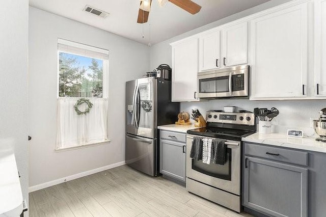 kitchen with white cabinetry, light wood-type flooring, appliances with stainless steel finishes, gray cabinets, and ceiling fan