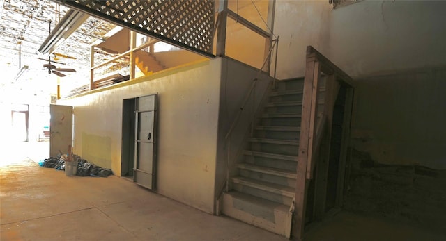 staircase with ceiling fan and concrete floors