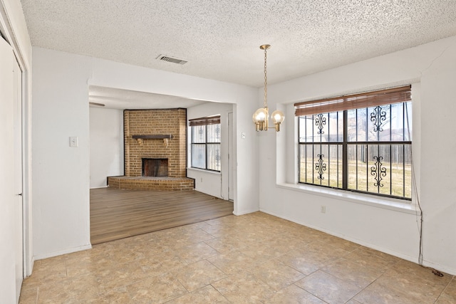 unfurnished dining area with an inviting chandelier, a fireplace, and a textured ceiling