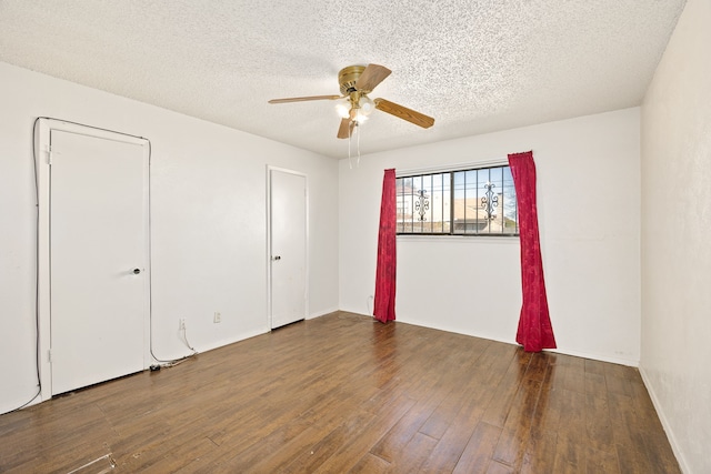 empty room with ceiling fan, dark hardwood / wood-style floors, and a textured ceiling