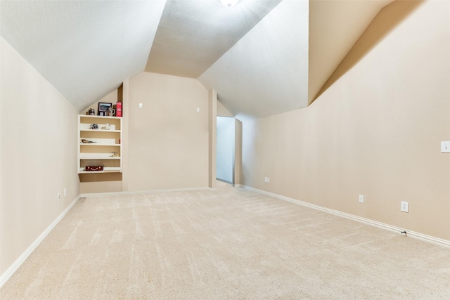 additional living space with lofted ceiling, light carpet, and built in features