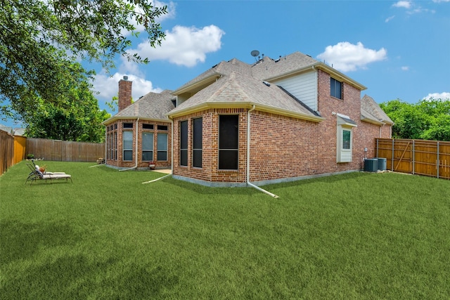 rear view of property with central AC unit and a lawn