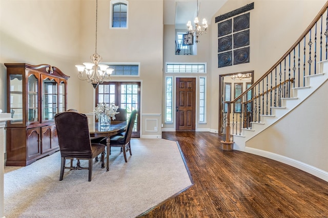 dining room with an inviting chandelier, a towering ceiling, and dark hardwood / wood-style flooring