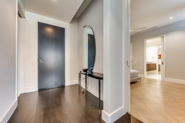 foyer entrance featuring parquet flooring, baseboards, and recessed lighting