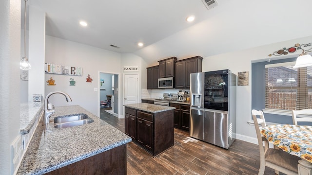 kitchen featuring sink, dark brown cabinets, stainless steel appliances, a center island, and light stone counters