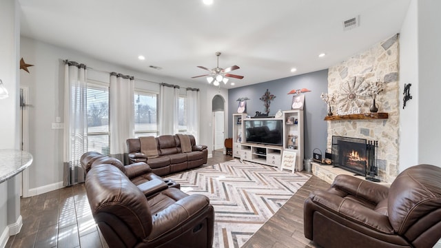 living room with ceiling fan and a stone fireplace