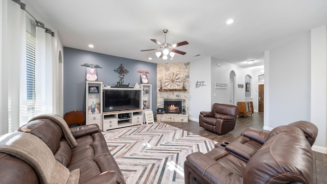 living room featuring hardwood / wood-style flooring, a stone fireplace, and ceiling fan