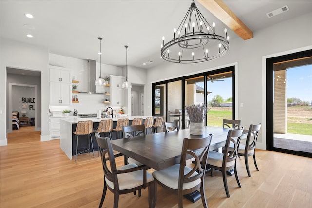 dining space with sink, light hardwood / wood-style flooring, beamed ceiling, and a healthy amount of sunlight