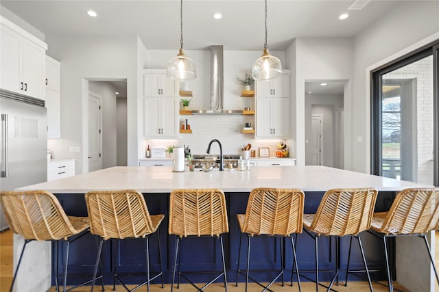 kitchen featuring white cabinetry, stainless steel appliances, and wall chimney range hood