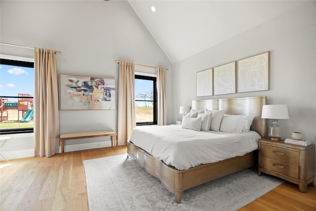 bedroom with access to outside, high vaulted ceiling, and light wood-type flooring