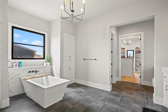 bathroom with an inviting chandelier, vanity, and a bathtub