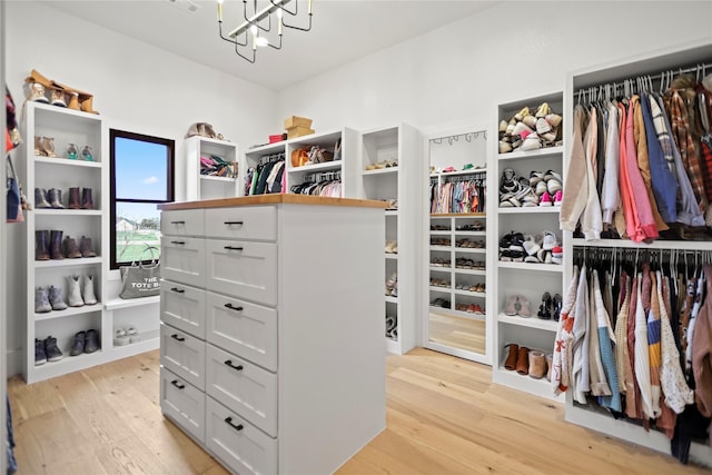 walk in closet with a notable chandelier and light wood-type flooring