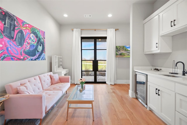 living room featuring french doors, sink, wine cooler, and light hardwood / wood-style flooring