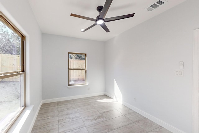 spare room featuring ceiling fan and a healthy amount of sunlight