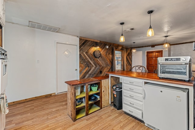 kitchen with butcher block countertops, stainless steel oven, hanging light fixtures, light wood-type flooring, and fridge