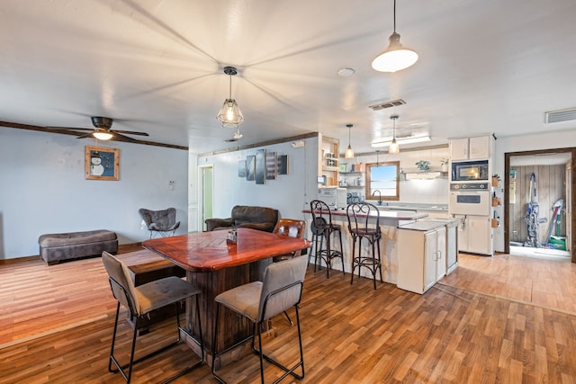 dining room with ceiling fan, sink, and light wood-type flooring