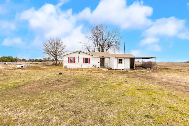 ranch-style home featuring a rural view, a front lawn, and a carport