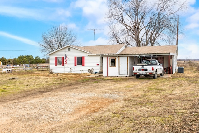 ranch-style home with central AC, a front lawn, and a carport