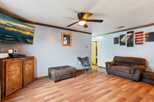 living room featuring ceiling fan, ornamental molding, and light wood-type flooring