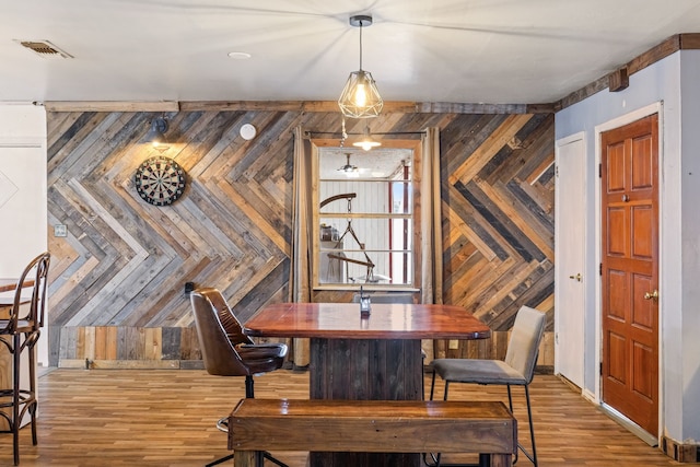 dining area with hardwood / wood-style floors and wooden walls