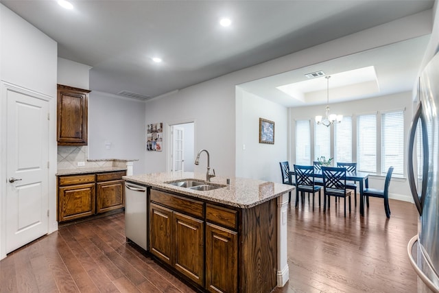 kitchen featuring appliances with stainless steel finishes, decorative light fixtures, sink, a raised ceiling, and a center island with sink